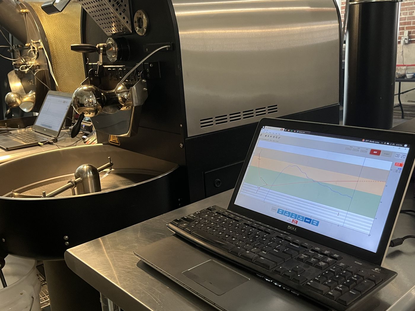 A roasting machine beside a laptop showing roast profiling software.