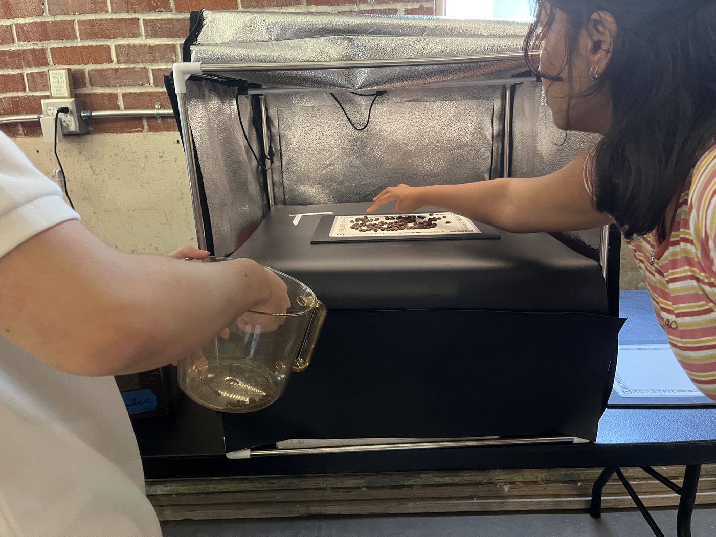A roaster loading beans into a small sample roaster.
