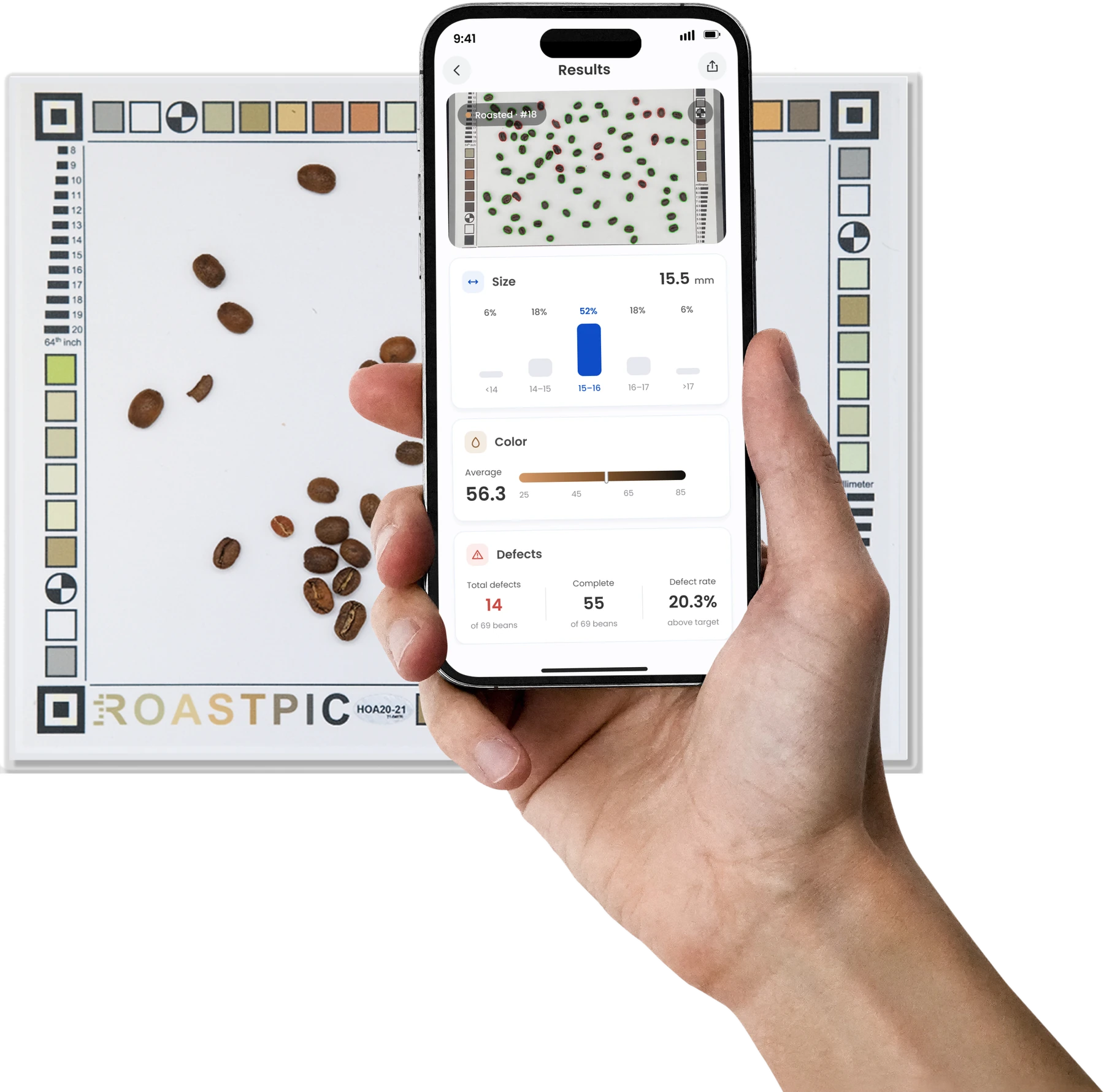 A hand holding a phone that shows RoastPic's measurement results, above the calibrated photo sheet of coffee beans